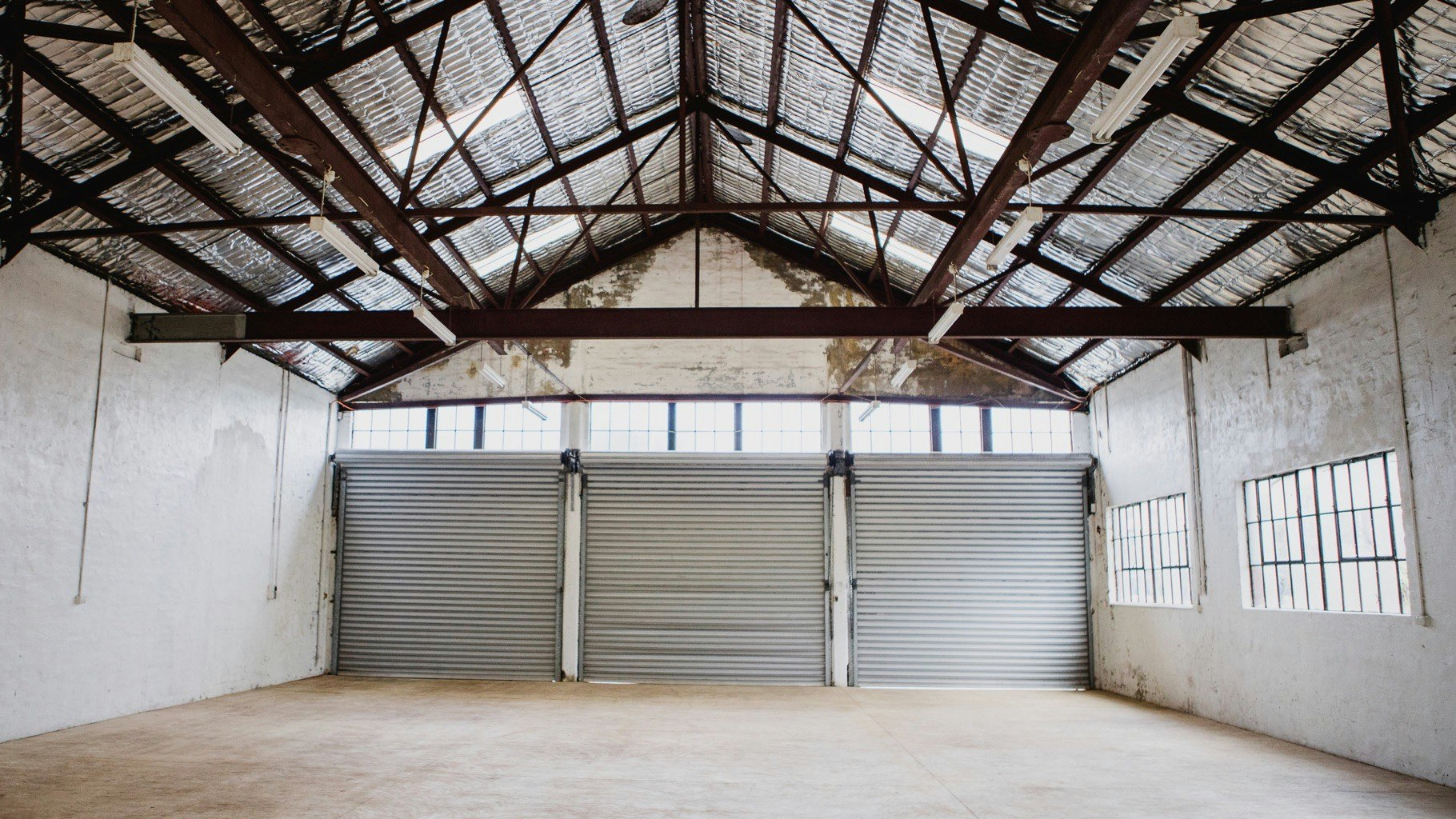 Empty barn space with roller doors and A-frame ceiling.